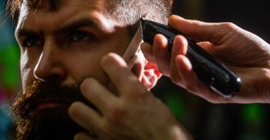 Saç kesimi konsepti. Hipster müşteri saçını kestiriyor. Berber dükkanını ziyaret eden bir adam. Berber saç makasıyla çalışıyor. Hipster müşteri saçını kestiriyor. Saç makasıyla berberin elleri