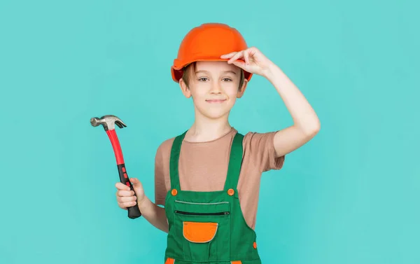 Kleine bouwer in helm en gezoem. Kind verkleed als arbeider bouwer. Kleine jongen met een helm op. Portret kleine bouwer in harde hoeden hamer. Kinderhelm, harde hoed. Hamer hameren — Stockfoto