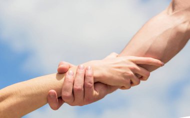 Yardım eli uzatıyorum. Mavi gökyüzü arka planında kadın ve erkeğin elleri. Yardım eli uzatıyorum. Kadın ve erkeğin elleri birbirine uzanıyor, destek oluyor. Dayanışma, şefkat ve yardım, kurtuluş.