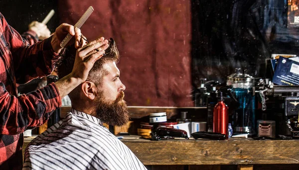 Cabeleireiro servindo cliente na barbearia. Homem visitando cabeleireiro na barbearia. Homem barbudo na barbearia. Trabalho na barbearia. Cabeleireiro corte de cabelo do cliente masculino — Fotografia de Stock