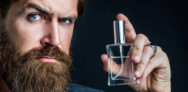 Perfume or cologne bottle, perfumery, cosmetics, scent cologne bottle, male holding cologne. Masculine perfumery, bearded man in a suit. Male holding up bottle of perfume. Man perfume, fragrance — Stock Photo, Image