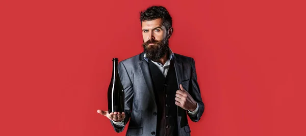 Un homme tenant une bouteille de champagne, du vin. Homme barbu avec une bouteille de champagne et de verre. La personne tient une bouteille de vin rouge dans une main — Photo