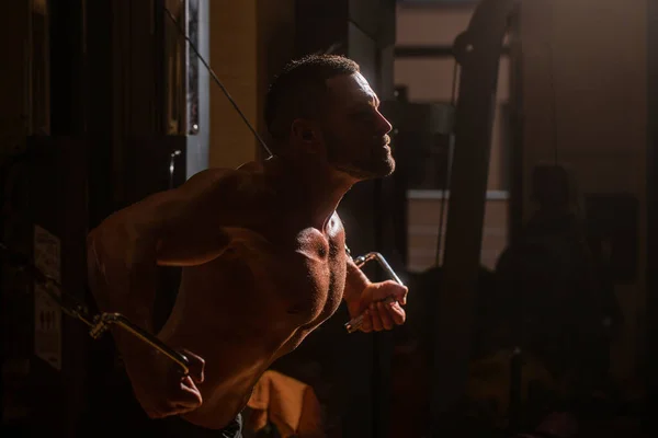 胸、ケーブルクロスオーバーのための体操の筋肉の人の試し。強力な男性の胴のABS 。フィットネスマンはジムで運動マシンケーブルクロスオーバーで運動を実行します。ジムで大きな筋肉を持つ男 — ストック写真