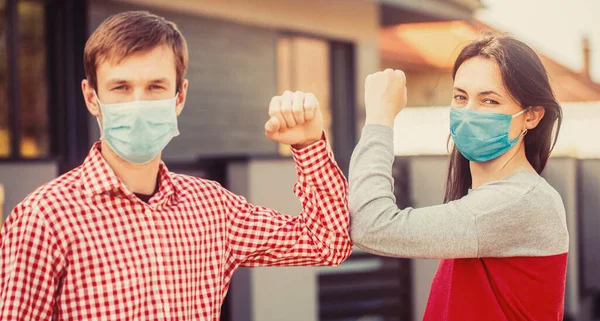 Elbows bump. Friends in protective medical mask on his face greet their elbows in quarantine