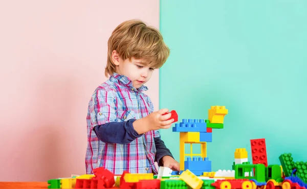 Educational toys for young children. Little boy playing with lots of colorful plastic blocks constructor. Boy playing with construction blocks at kindergarten. Child playing with colorful toy blocks