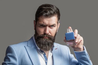 Erkeksi parfüm, takım elbiseli sakallı adam. Elinde parfüm şişesi tutan bir erkek. Erkek parfümü, parfüm. Parfüm ya da parfüm şişesi, parfüm, kozmetik, parfüm şişesi, kolonya tutan erkek.