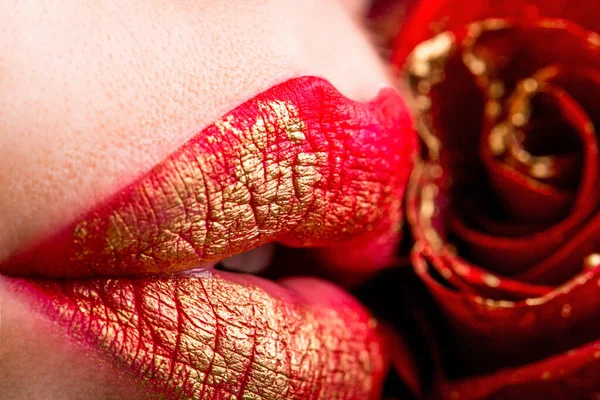 Kırmızı güllü kadın dudaklarının yakın çekimi. Kırmızı rujlu seksi kadın dudakları. Kadın dudakları ve kırmızı çiçek. Şehvetli dudaklar. Gül çiçekli kadın. Kırmızı rujlu seksi kadın dudakları. — Stok fotoğraf