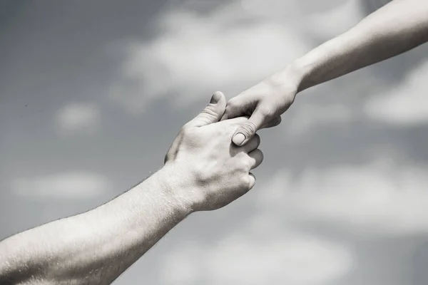 Solidarity, compassion, and charity, rescue. Giving a helping hand. Hands of man and woman on blue sky background. Lending a helping hand. Black and white — Stockfoto