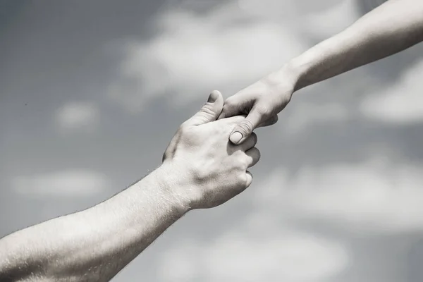 Solidarity, compassion, and charity, rescue. Giving a helping hand. Hands of man and woman on blue sky background. Lending a helping hand. Black and white — Foto Stock