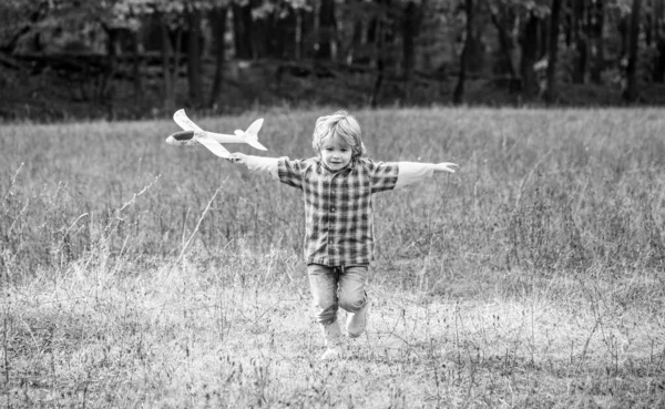 Little boy with plane. Little kid dreams of being a pilot. Child playing with toy airplane. Happy child playing. Black and white — Stock Photo, Image