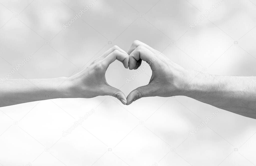 Girl and male hand in heart form love blue sky. Female and man hands in the form of heart against the sky. Black and white