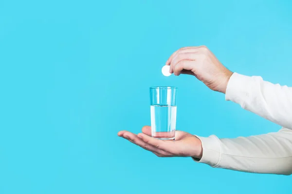 Weiße Pille und ein Glas Wasser in Menschenhänden. Gesundheitskonzept. Großaufnahme eines Mannes, der eine Pille hält. Glas Wassertablette vorhanden. Glas mit Tablette in Wasser mit Blasen — Stockfoto