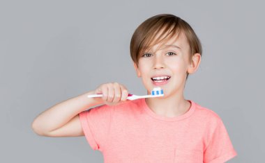 Neşeli çocuk diş fırçalarını gösteriyor. Diş temizleyen küçük çocuk. Diş hijyeni. Küçük mutlu çocuk dişlerini fırçalıyor. Çocuk dişlerini fırçalıyor. Erkek diş fırçası beyaz diş macunu. Sağlık, diş sağlığı...