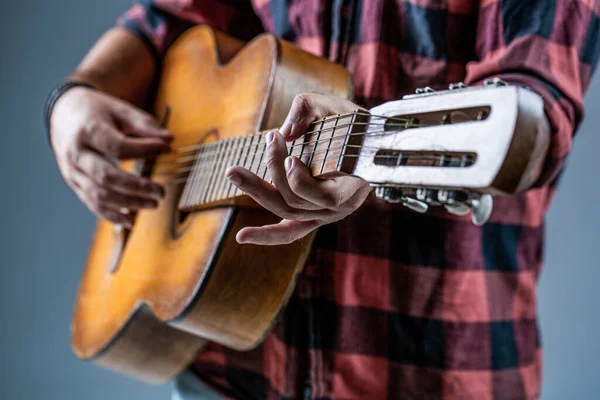 Gitary i struny. Facet gra na gitarze, trzyma gitarę akustyczną w rękach. Koncepcja muzyki. Gitarzysta gra. Zagraj na gitarze. Hipster siedzi w pubie. Muzyka na żywo — Zdjęcie stockowe