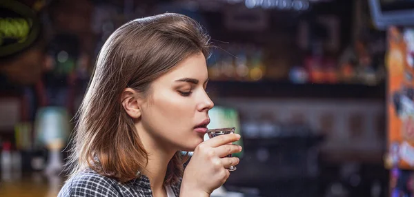 Drunk woman holding a glass of whisky or rum. Woman in depression. Young beautiful woman drinking alcohol. Scotch whiskey glass isolated at bar or pub in alcohol abuse and alcoholic concept — Stock Photo, Image