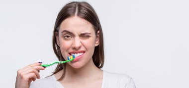 Diş sağlığı geçmişi. Diş fırçasıyla mükemmel ve sağlıklı dişleri kapat. Elinde diş fırçası tutan gülümseyen sevimli bir kadının portresi. Güzel dişleri olan gülümseyen bir kadın diş fırçası tutuyor.