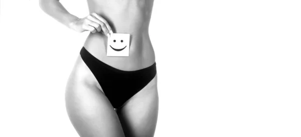 검은 팬티를 입고 행복 한 미소짓는 얼굴로 카드를 들고 있는 건강 한 여성의 모습이 감춰져 있다. 위장관 건강, 소화가 잘 되는 개념. 흑백 — 스톡 사진