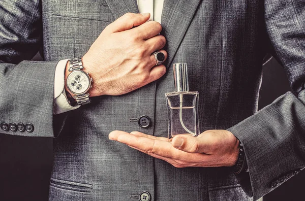 Male holding up bottle perfume. Hand in with wrist watch in a business suit. Perfume or cologne bottle and perfumery, cosmetics, scent cologne bottle, male holding cologne — Stock Photo, Image