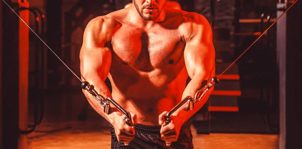 Abdominales y bíceps. Hombre de fitness ejecutar ejercicio con máquina de ejercicio Cable Crossover en el gimnasio. Hombre guapo con grandes músculos en el gimnasio. Máquina en el gimnasio —  Fotos de Stock