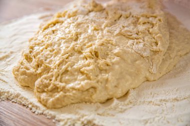 Hamur işlerinin arka planı. Pizza ya da ekmek pişirmek için taze çiğ hamur. Yakın çekim mayalanmış hamur, ev yapımı. Makro seçici odak ham hamur dokusu arkaplanı.