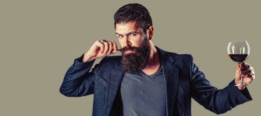 Sommelier adam, degustator, şaraphane. Şampanya şişeli adam. Takım elbiseli adam köpüklü kırmızı şarapla kadeh kaldırıyor. Şişede kırmızı şarap, şarap kadehi..