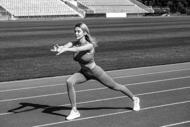 Spor egzersizleri ve stadyumda esneme hareketleri. Beden eğitimi kızı. Formda kız dışa doğru hamle yapıyor. Beden eğitimi eğitimi. Spor dersi. Siyah ve beyaz.