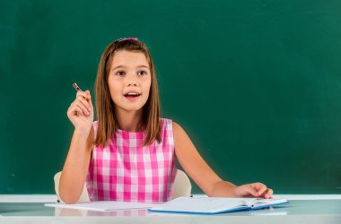 Okula dönelim. Okul malzemeleri. Derste öğrenci, derste sınıf. Şirin kız, sınıftaki bir masada defterler ve ders kitaplarıyla oturuyor. Öğrenci bir deftere yazar..