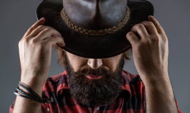 Şapkalı kovboylar. Yakışıklı sakallı maço. Tıraşsız kovboylar. Amerikan kovboyu. Deri Kovboy Şapkası. Kovboy şapkası takan genç adamın portresi.