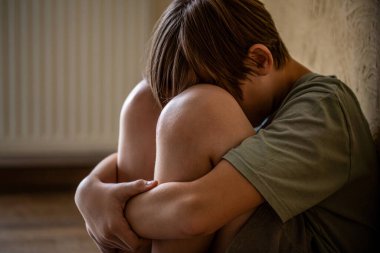 Evde tek başına oturan üzgün çocuk depresyondan muzdarip. Yüzünü örten korkmuş, küçük bir çocuk. Çocuk bağırıyor, elleriyle yüzünü kapatıyor, zorbalık yapıyor. Yalnız bir çocuk odada oturuyor..