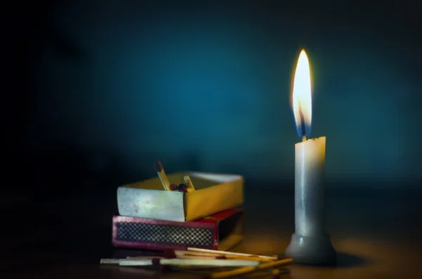 Pie en vela oscura iluminada con caja de fósforos y palos acostados en floo — Foto de Stock