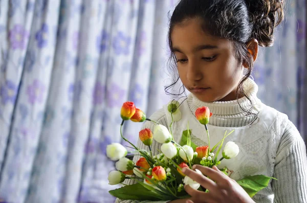 Ragazza bambino guardando fiori ritratto al coperto — Foto Stock