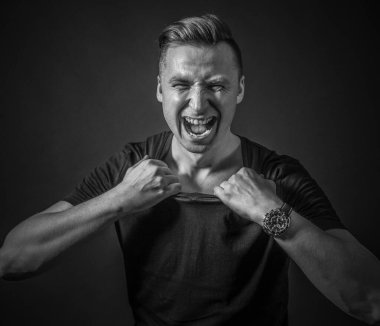 Kızgın adam gömleğini yırtarak açmaya çalışıyor.