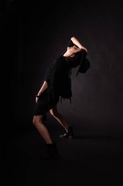 Siyah arka planda poz veren genç bir kadın model..