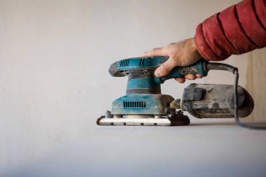 Elektrikli kum makinesi kullanarak tahta zımparalayan adam..