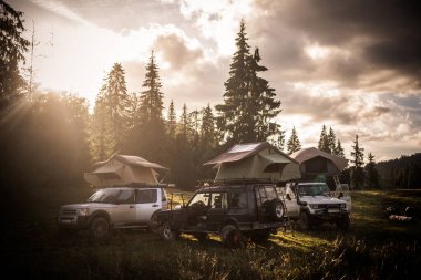Gün batımında, ormanda çatıda çadırları olan bazı off-road arabaları..