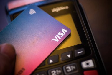 Bükreş, ROMANIA - 17 Mayıs 2021: POS terminali yakınlarında VISA kartı tutan bir kişinin resimli editörlük konsepti. 