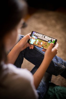 Bükreş, ROMANIA - 10 Mayıs 2021: Cep telefonuyla Minecraft oyunu oynayan bir çocuğun resimli editör konsepti.