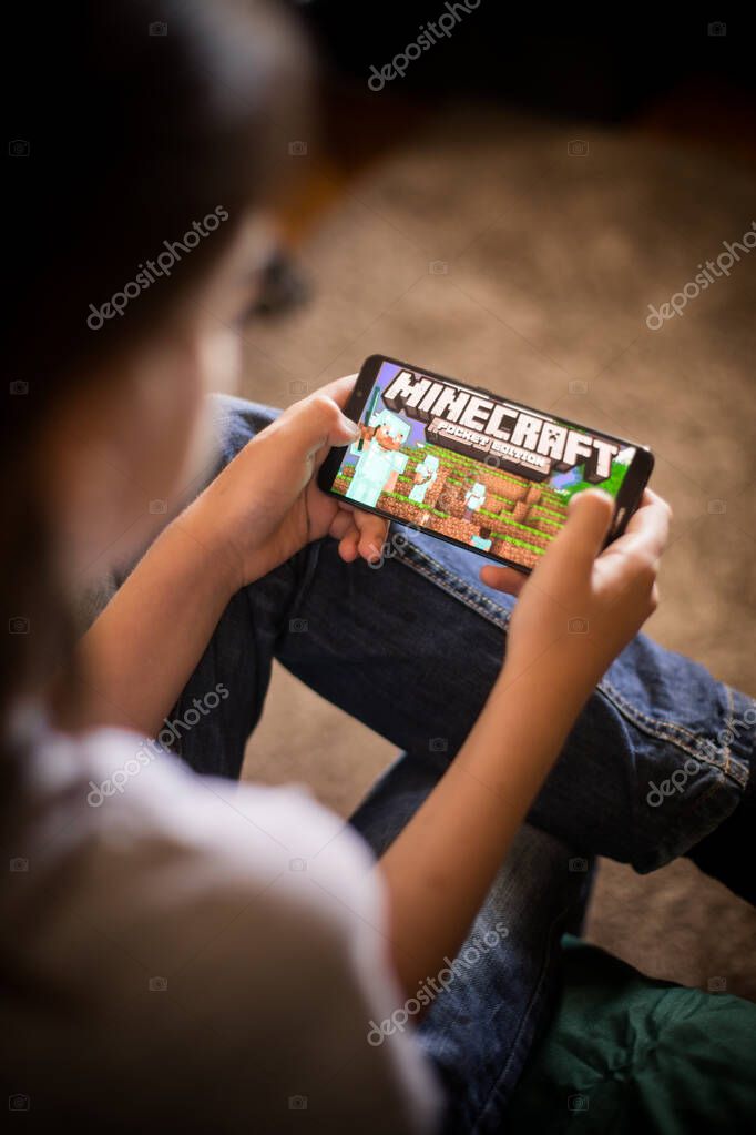 Bucharest, ROMANIA - May 10, 2021: Illustrative editorial concept image of a child playing Minecraft game on a mobile phone.