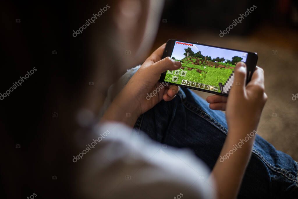 Bucharest, ROMANIA - May 10, 2021: Illustrative editorial concept image of a child playing Minecraft game on a mobile phone.