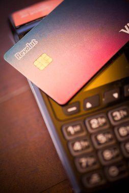 Bükreş, ROMANIA - 17 Mayıs 2021: POS terminali yakınlarında Revolut VISA kartı tutan kişinin resimli editörlük konsepti. 