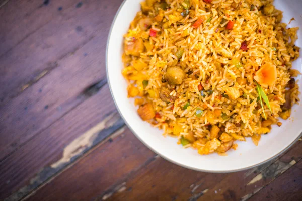 Sebzeli ve tavuklu bir tabak Asya pirinci yakın çekim. Kopya alanı olan ahşap bir masada..