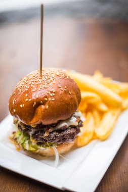 Tabakta taze bir hamburger ve patates kızartmasının yakın plan resmi..