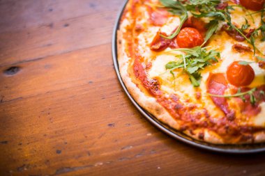 Tahta bir masada, fotokopi alanı olan bir pizzanın yakın plan çekimi..
