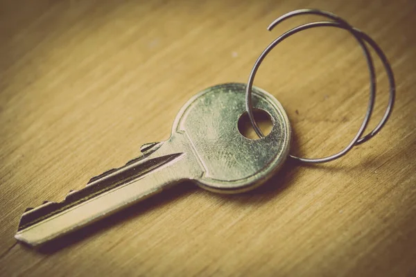 Close up shot of a vintage key on a wooden background.