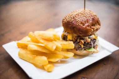 Tabakta taze bir hamburger ve patates kızartmasının yakın plan resmi..