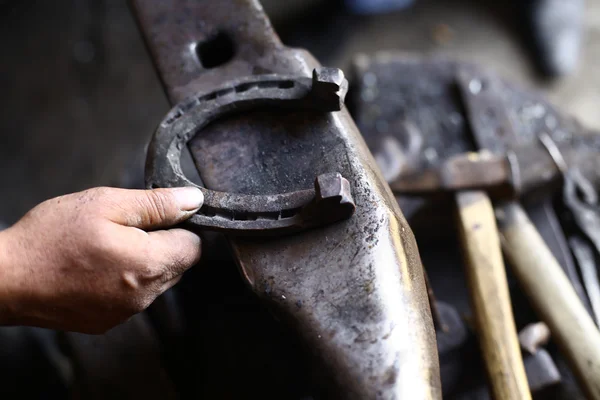 Hand met een hoefijzer op een aambeeld — Stockfoto