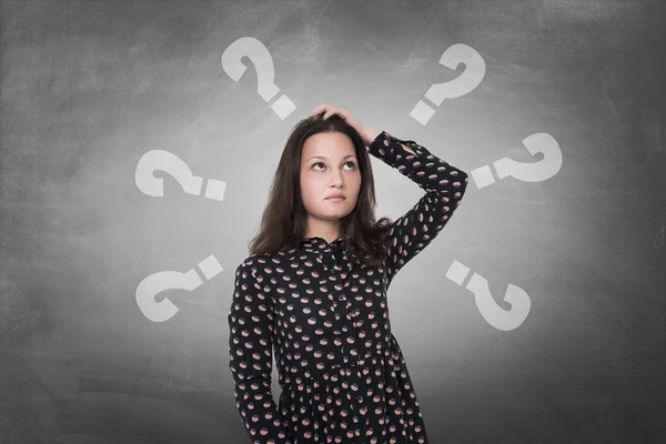 Beautiful woman with questioning expression and question marks above her head — Stock Photo, Image