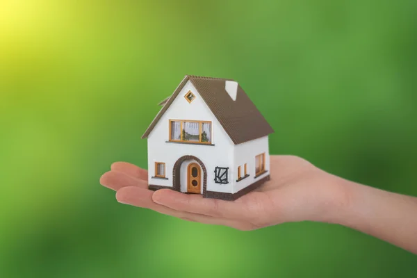 Haus in den Händen auf grünem Hintergrund — Stockfoto