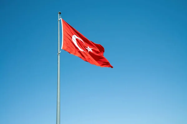 Rüzgarlı mavi arkaplanda dalgalanan Türk Bayrağı. — Stok fotoğraf