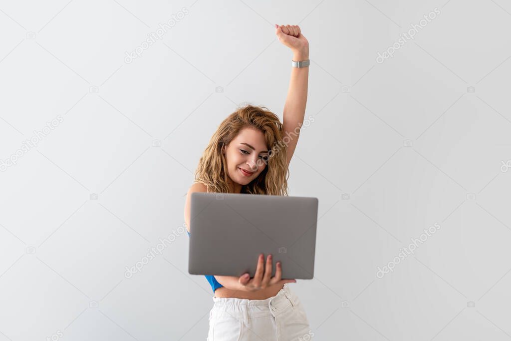 Young , beautiful woman hold her fist up and become happy, while she see the results on the screen. Victory and success concept